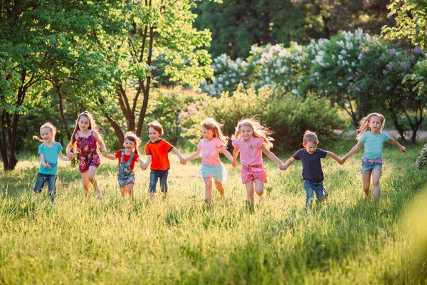 Μεγάλη ομάδα παιδιών, φίλων αγόρια και κορίτσια που τρέχουν στο πάρκο την ηλιόλουστη καλοκαιρινή μέρα με casual ρούχα . — Φωτογραφία Αρχείου