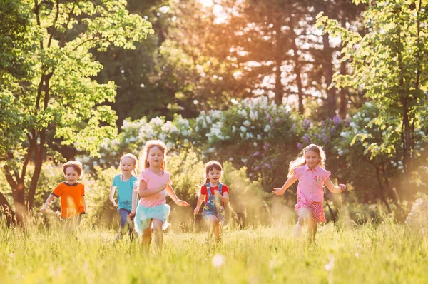 Gran grupo de niños, amigos, niños y niñas corriendo en el parque en el soleado día de verano con ropa casual . —  Fotos de Stock