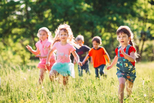 Büyük bir grup çocuk, arkadaşlar güneşli bir yaz gününde parkta günlük kıyafetlerle koşuşturuyorlar. . — Stok fotoğraf