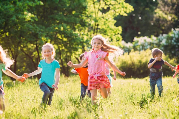 Eine große Gruppe von Kindern, befreundeten Jungen und Mädchen läuft an einem sonnigen Sommertag in Freizeitkleidung durch den Park . — Stockfoto