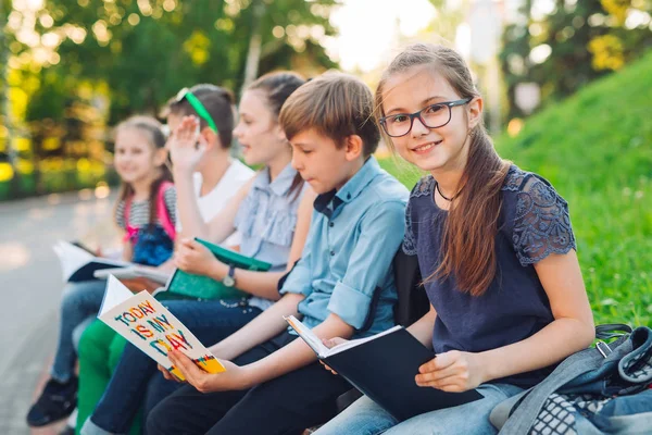 Buon Ritratto dei compagni di scuola. Compagni di scuola seduti con libri in una panchina di legno in un parco cittadino e che studiano nelle giornate di sole. — Foto Stock