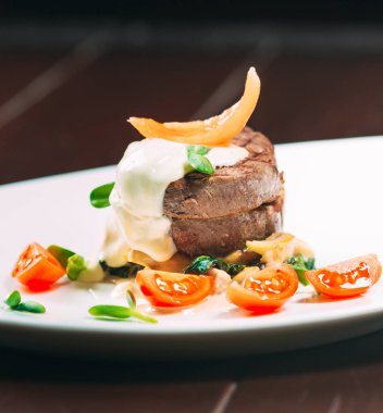 Beyaz tabakta ıspanaklı dana madalyonu.