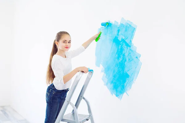 Oprava v bytě. Šťastné dítě dívka maluje stěnu s modrým nátěrem, — Stock fotografie
