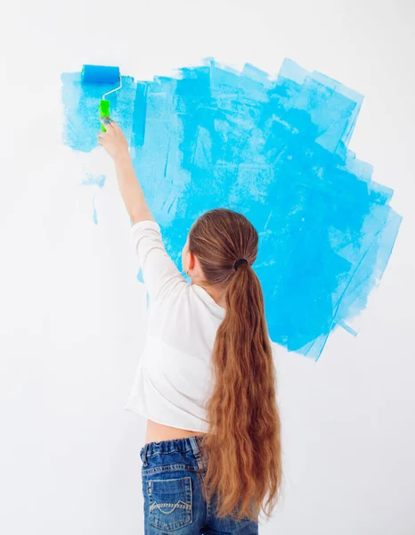 Reparación en el apartamento. Niña feliz pinta la pared con pintura azul, — Foto de Stock