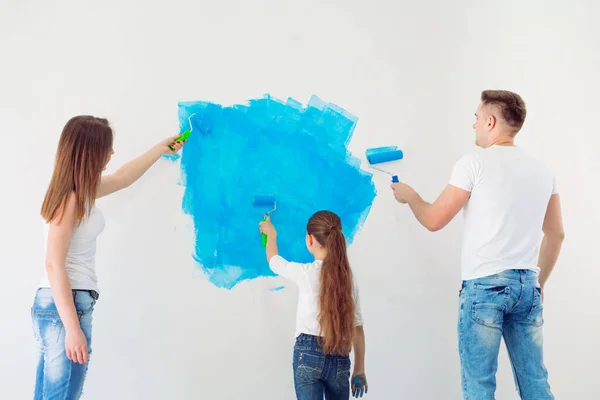 Madre, padre e hija pintando la pared en su nuevo hogar. — Foto de Stock