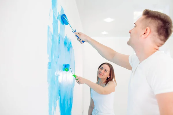 Pareja feliz pintando paredes en su nueva casa lista para vivir juntos. — Foto de Stock