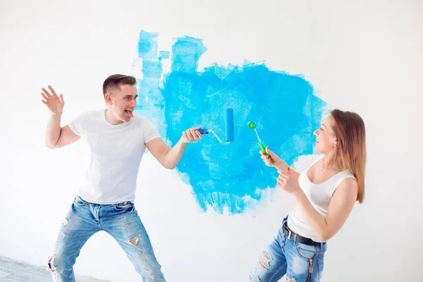 Šťastný pár malování stěn v jejich novém domě připraveni žít společně. — Stock fotografie