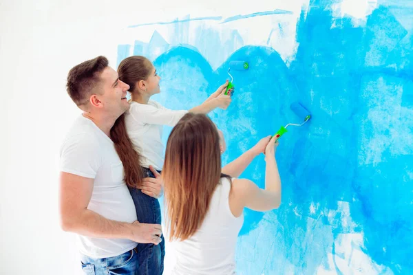 Madre, padre e hija pintando la pared en su nuevo hogar. — Foto de Stock
