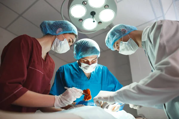 外科手術室で働く外科医のグループ。患者を救うための医療用具を保持する保護マスクを身に着けている蘇生医療チーム。手術と緊急時のコンセプト. — ストック写真