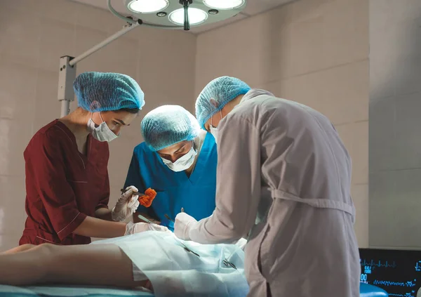 外科手術室で働く外科医のグループ。患者を救うための医療用具を保持する保護マスクを身に着けている蘇生医療チーム。手術と緊急時のコンセプト. — ストック写真