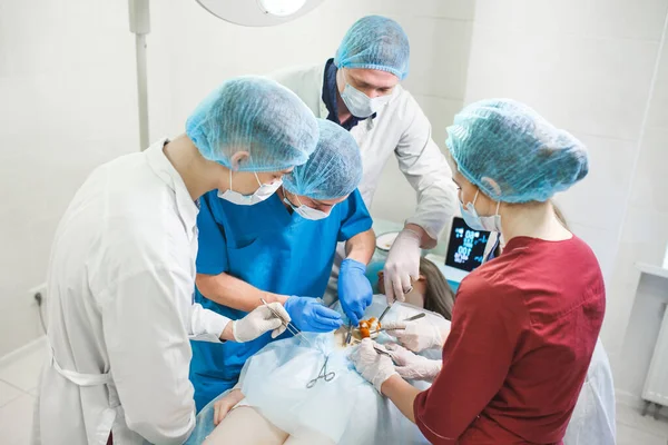 Groupe de chirurgiens au travail opérant en salle d'opération. Équipe de médecine de réanimation portant des masques de protection tenant des outils médicaux en acier sauvant le patient. Chirurgie et concept d'urgence. — Photo