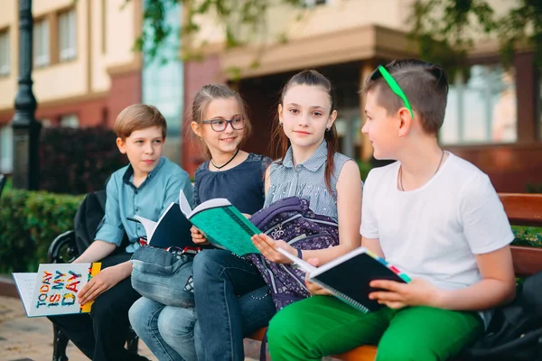 Szczęśliwego Portretu kolegów ze szkoły. Koledzy ze szkoły siedzą z książkami w drewnianej ławce w parku miejskim i uczą się w słoneczny dzień. — Zdjęcie stockowe