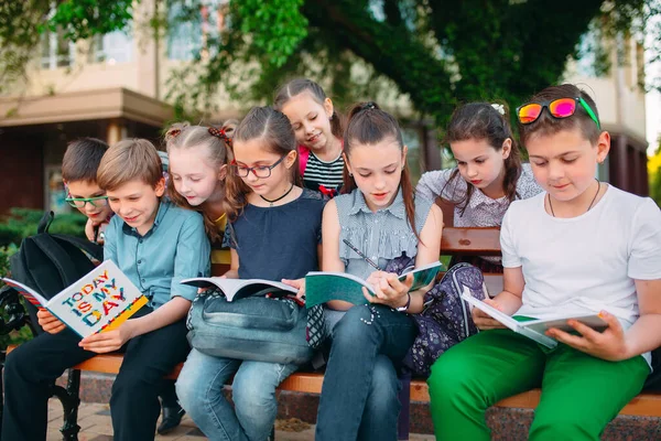 좋아 하는 학창 시절의 추억. 학교 친구들이 도시 공원의 나무 벤치에 앉아 책을 가지고 화창 한 날 연구하고 있다. — 스톡 사진