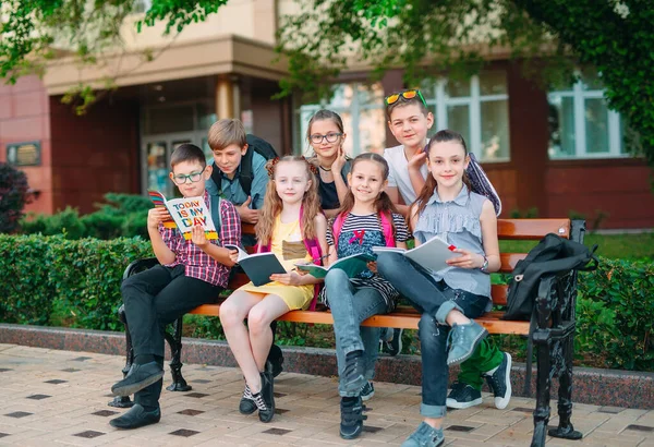 Szczęśliwego Portretu kolegów ze szkoły. Koledzy ze szkoły siedzą z książkami w drewnianej ławce w parku miejskim i uczą się w słoneczny dzień. — Zdjęcie stockowe