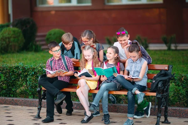 Šťastný portrét spolužáků. Spolužáci sedící s knihami v dřevěné lavičce v městském parku a studující za slunečného dne. — Stock fotografie