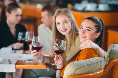 Arkadaşlar şarap içerek, konuşarak ve gülümseyerek eğlenirler..