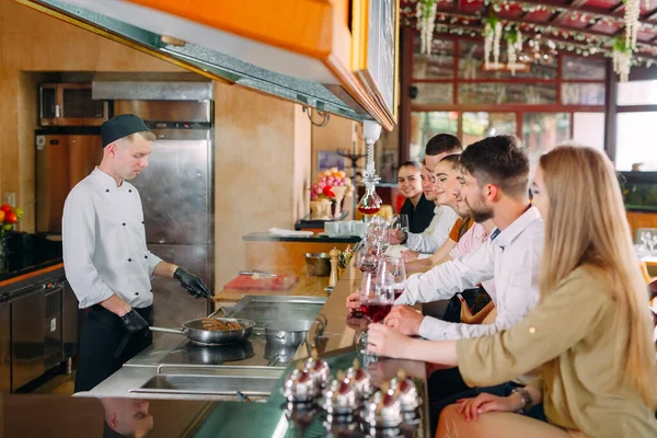 El chef prepara comida frente a los visitantes en el restaurante —  Fotos de Stock