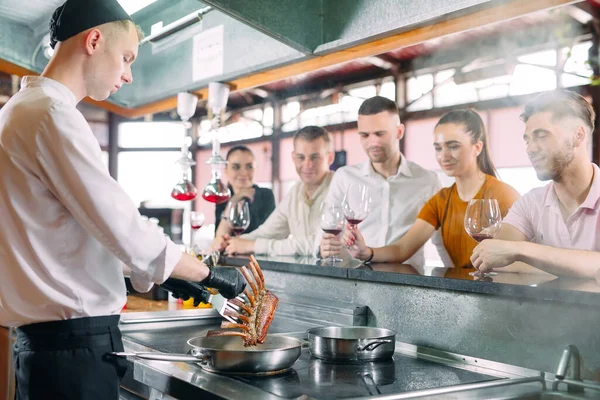 El chef prepara comida frente a los visitantes en el restaurante —  Fotos de Stock