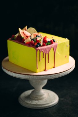 İncir, ahududu, yabanmersini ve limonla süslenmiş sarı turunçgil keki..