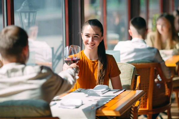 Um jovem casal bebendo vinho em um restaurante perto da janela . — Fotografia de Stock
