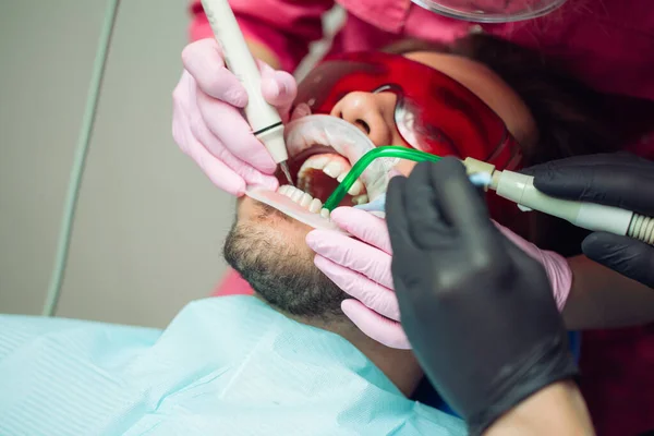 Professional teeth cleaning. Dentist cleans the teeth of a male patient. — Stock Photo, Image