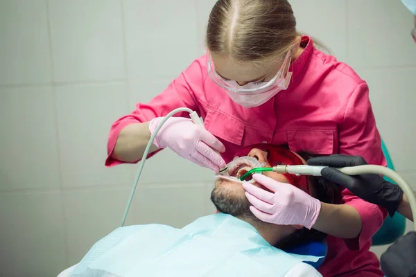 Professional teeth cleaning. Dentist cleans the teeth of a male patient. — Stock Photo, Image