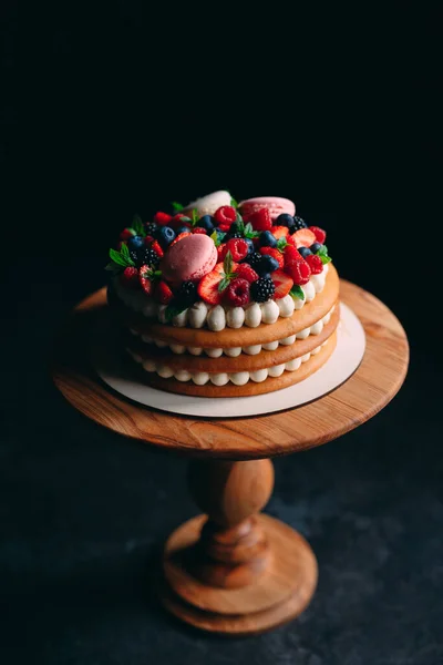 Pastel de frutas. Pastel decorado con bayas en un soporte de madera sobre un fondo negro. — Foto de Stock