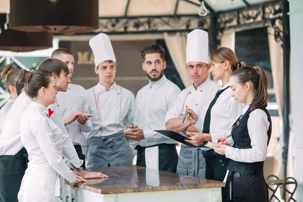 Restaurant manager and his staff in terrace. interacting to head chef in restaurant.