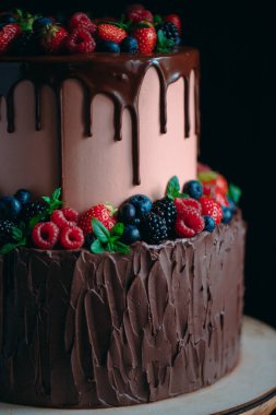 Tahta üzerinde meyveli çikolatalı kek siyah arka planda duruyor..