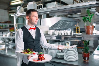 Garson lokantada görev başında. Garson bulaşıkları taşıyor.