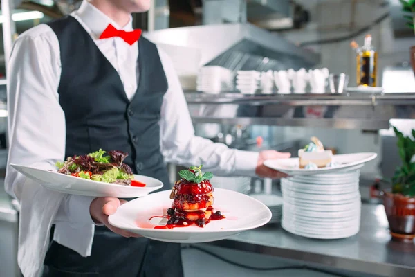 Garson lokantada görev başında. Garson bulaşıkları taşıyor.