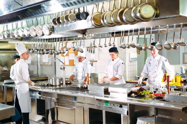 Moderne Küche. Köche bereiten die Mahlzeiten auf dem Herd in der Küche des Restaurants oder Hotels zu. Das Feuer in der Küche — Stockfoto