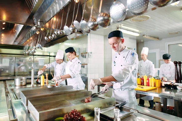 Modern konyha. A szakácsok az étterem vagy szálloda konyhájában, a kályhán készítenek ételeket. A tűz a konyhában. — Stock Fotó