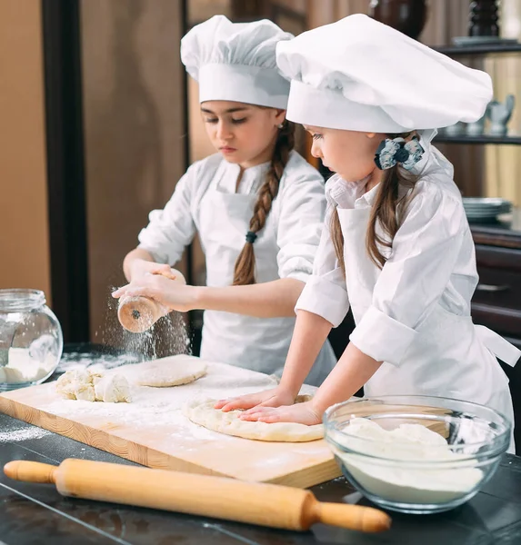 Meninas engraçadas crianças estão preparando a massa na cozinha . — Fotografia de Stock