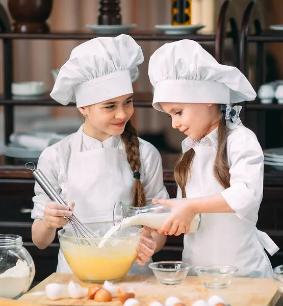Meninas engraçadas crianças estão preparando a massa na cozinha . — Fotografia de Stock