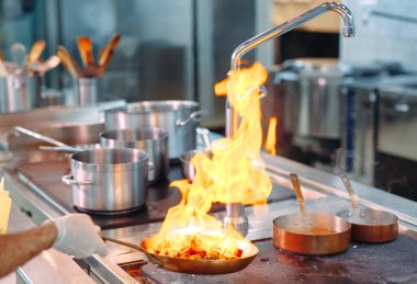 Şef tavada sebze pişiriyor. Sığ dof.