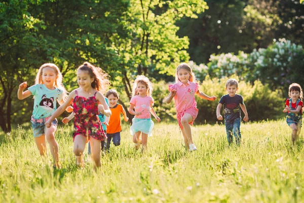 Gran grupo de niños, amigos, niños y niñas corriendo en el parque en el soleado día de verano con ropa casual . —  Fotos de Stock