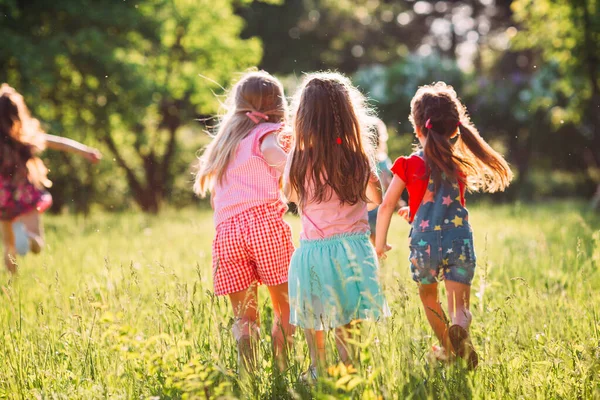 Eine große Gruppe von Kindern, befreundeten Jungen und Mädchen läuft an einem sonnigen Sommertag in Freizeitkleidung durch den Park . — Stockfoto