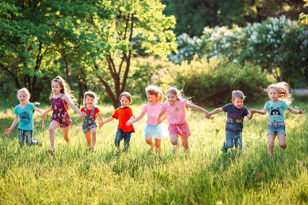 Eine große Gruppe von Kindern, befreundeten Jungen und Mädchen läuft an einem sonnigen Sommertag in Freizeitkleidung durch den Park . — Stockfoto