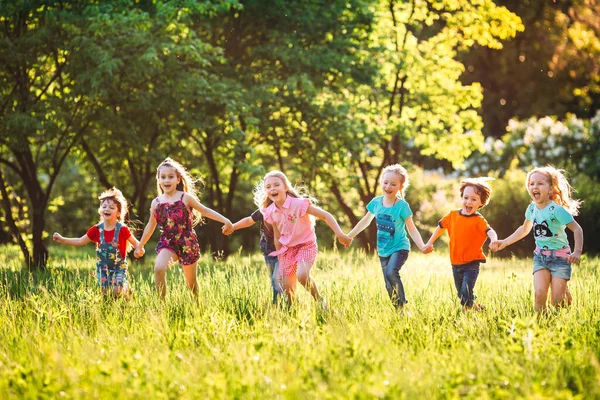 Eine große Gruppe von Kindern, befreundeten Jungen und Mädchen läuft an einem sonnigen Sommertag in Freizeitkleidung durch den Park . — Stockfoto