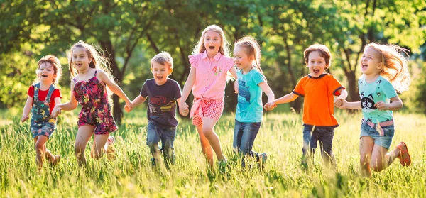 Grande gruppo di bambini, amici ragazzi e ragazze che corrono nel parco nella soleggiata giornata estiva in abiti casual . — Foto Stock