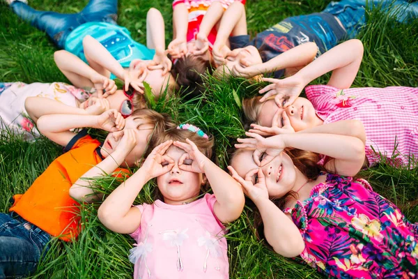 A group of children lying on the green grass in the Park. The interaction of the children. — Stock Photo, Image