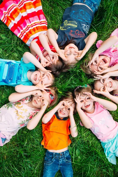 Eine Gruppe Kinder liegt auf dem grünen Rasen im Park. Die Interaktion der Kinder. — Stockfoto