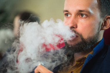 Bir kafede nargile içmek. Adam duman üflüyor..