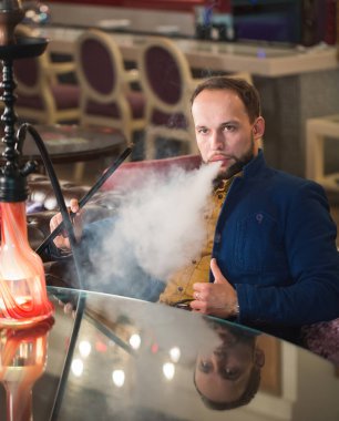 Bir kafede nargile içmek. Adam duman üflüyor..