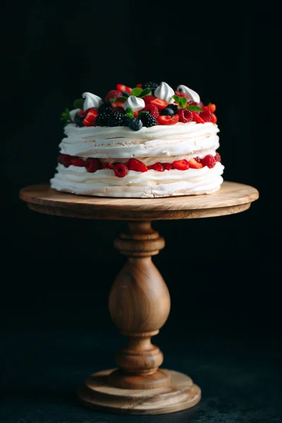 フルーツケーキ。黒を基調とした木製のスタンドにベリーで飾られたケーキ。. — ストック写真