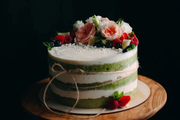 Bolo é decorado com flores em um fundo escuro. — Fotografia de Stock