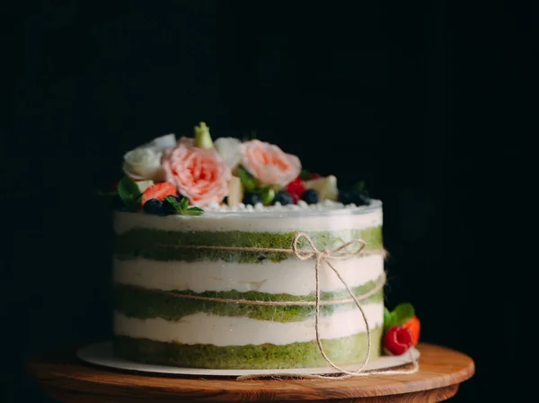 ケーキは暗い背景に花で飾られています。. — ストック写真