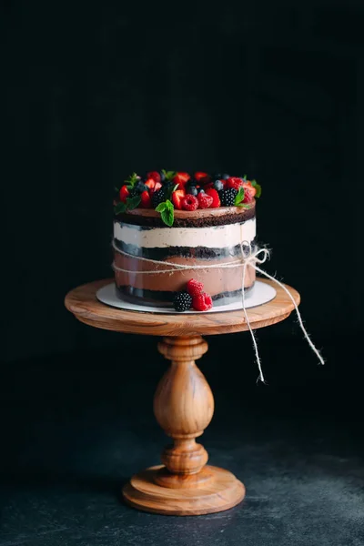 Meyveli kek. Kek, siyah arka plandaki ahşap bir stantta böğürtlenlerle süslenmiş.. — Stok fotoğraf