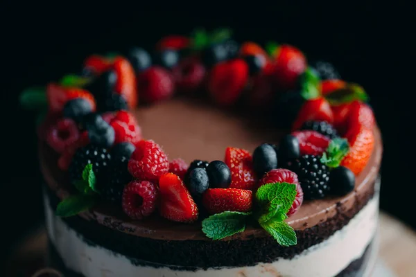과일 케익이요. 검은 배경의 나무 받침대에 열매로 장 식 된 케이크. — 스톡 사진